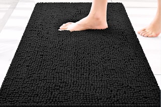 Lifestyle image of the Smiry Chenille Bathroom rug in the color black being stepped on