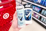hand holding two degree deodorant sticks in front of a target cart