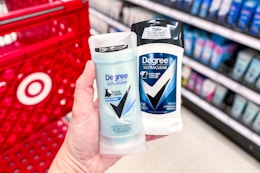 hand holding two degree deodorant sticks in front of a target cart