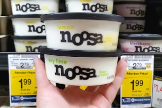 A hand holding two containers of Noosa yoghurt