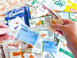 hands holding a mix of expired fast food coupons 
