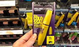 a hand holding a pack with a yellow mascara wand