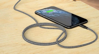 a braided lightning charger cable plugged into a phone resting on a table