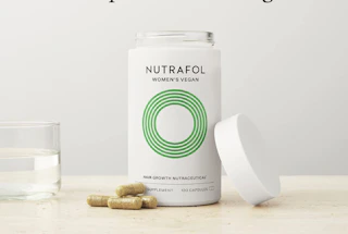 vitamins in a bottle and on a table with a cup of water