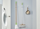 a broom, mop, and dustpan in grippers on a wall