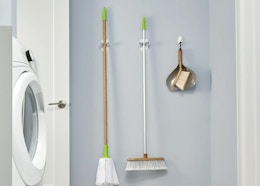 a broom, mop, and dustpan in grippers on a wall