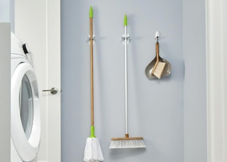 a broom, mop, and dustpan in grippers on a wall