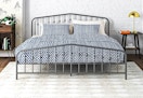 Lifestyle image of the king Novogratz Bushwick Metal Bed in Gunmetal Gray in a bedroom setting