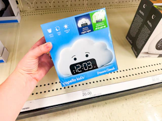 hand holding a kids wake up alarm clock in front a target shelf