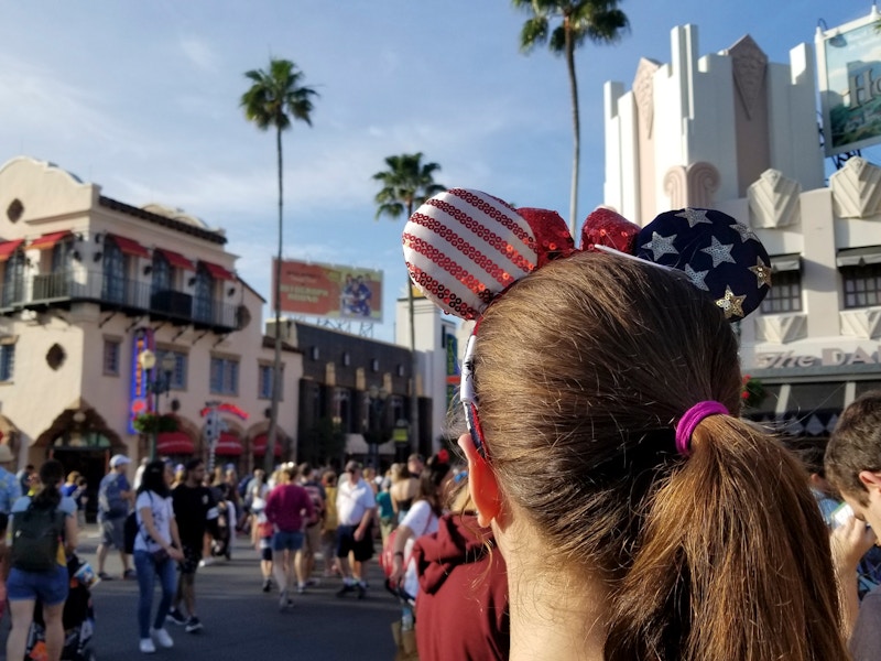 American flag printed Mickey Mouse ears on a woman in a Disney park.