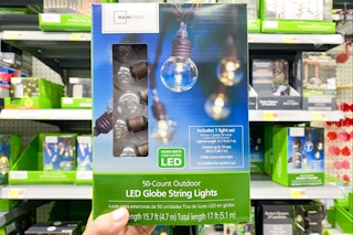 hand holding a box of 5-count Mainstays globe string lights in front of the outdoor lighting area