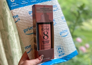 hand holding a bottle of l'oreal elvive 8 second wonder water with an amazon package