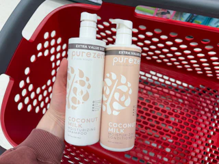 hand holding 2 purezero shampoo bottles over a target cart