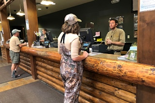 A woman talking to a Cabela's employee at the customer service desk.