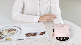 a person with their hand in a pink hand massager 