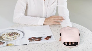 a person with their hand in a pink hand massager 
