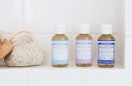 Three soap bottles and a sponge on a shelf in the shower