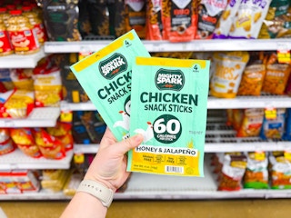 hand holding two packs of mighty spark snack sticks in walmart aisle