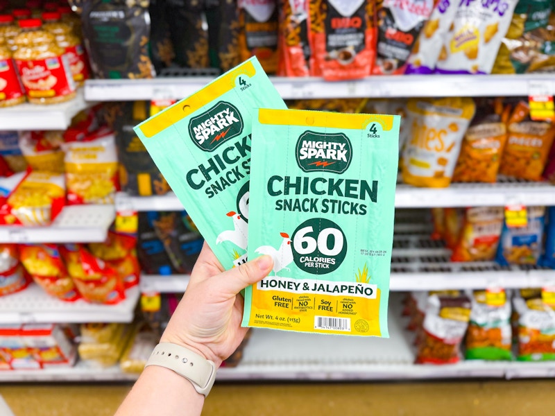 hand holding two packs of mighty spark snack sticks in walmart aisle