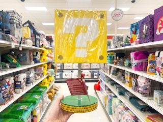 A kid's lamp held up by hand in front of a store aisle.