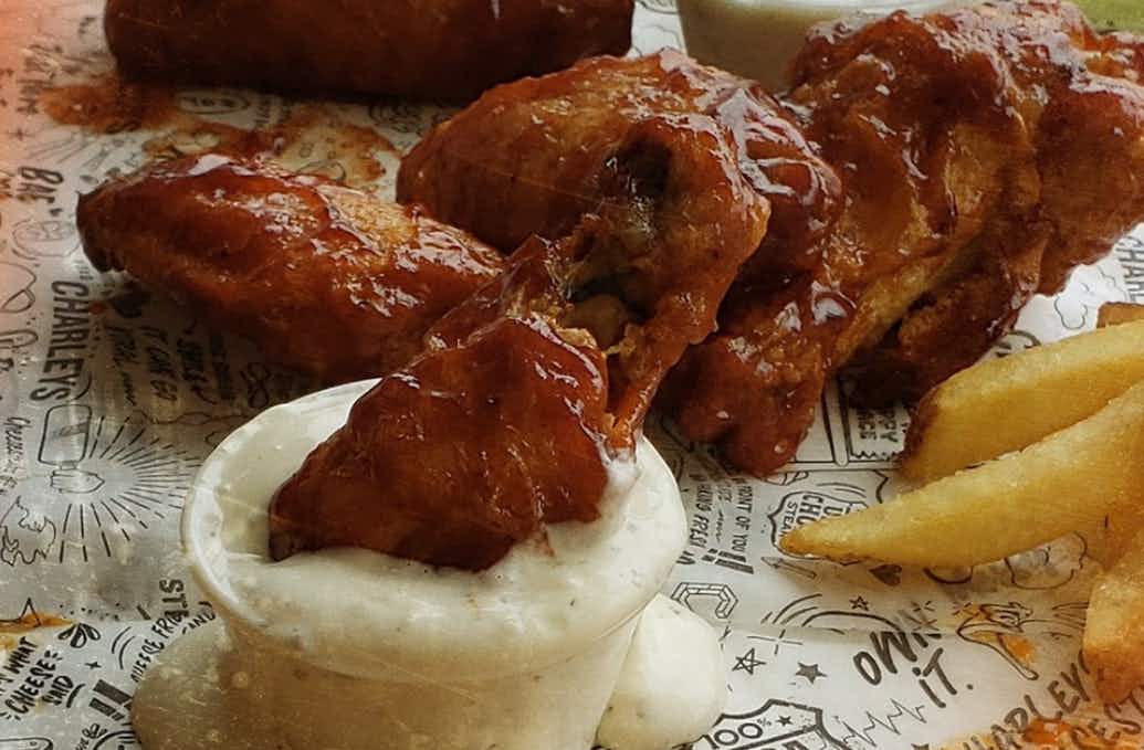 a photo of charleys cheesesteak wings being dipped into ranch. taken from their instagram page.