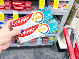 hand holding two tubes of colgate toothpaste