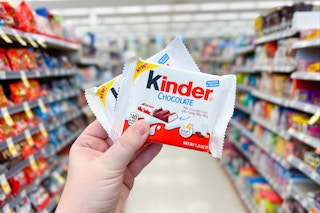 hand holding two kinder chocolate bars in store aisle