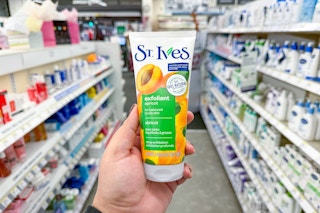 person holding a st ives face scrub in an aisle