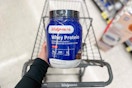 hand holding walgreens chocolate whey protein over cart