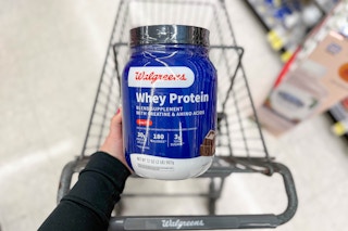 hand holding walgreens chocolate whey protein over cart