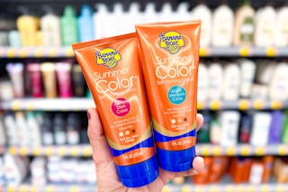 person holding 2 bottles of banana boat tanning lotion