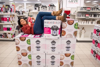 A woman laying on a pile of Instant Pot cookers on display for Black Friday deals at Kohl's.