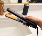 a hand holding a flat iron over a bathroom sink