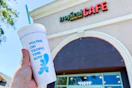 a peerson holding up a smoothie in front of a tropical smoothie cafe