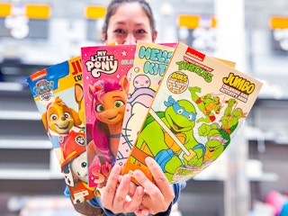 woman holding four coloring books in walmart aisle