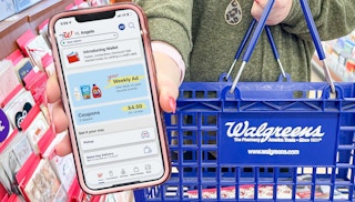 woman holding cellphone with walgreens app while holding walgreens basket