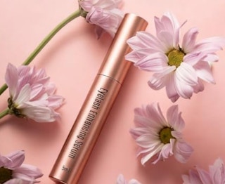 a pink tube of lash serum near flowers