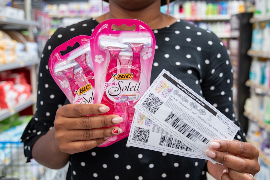 A person holder 2 packs of razors in one hand an two coupons in the other hand.