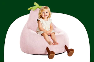 Stock image of a small child sitting in a pink eggplant chair