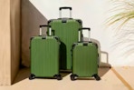 Lifestyle image of the green hardside luggage set from the brand Hikolayae at Home Depot (outdoor setting)