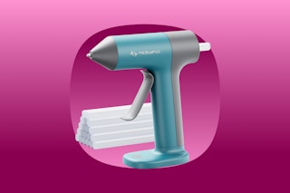 A teal and grey hot glue gun with a place to insert glue in the back so it shoots out hot. Glue sticks are behind it.