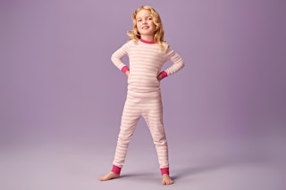 Lifestyle image of toddler wearing a Joyspun pajama set in pink stripes (purple background) 
