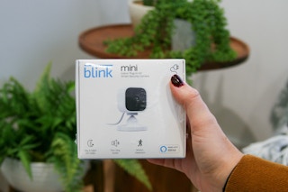 person holding blink mini indoor plug-in hd smart security camera