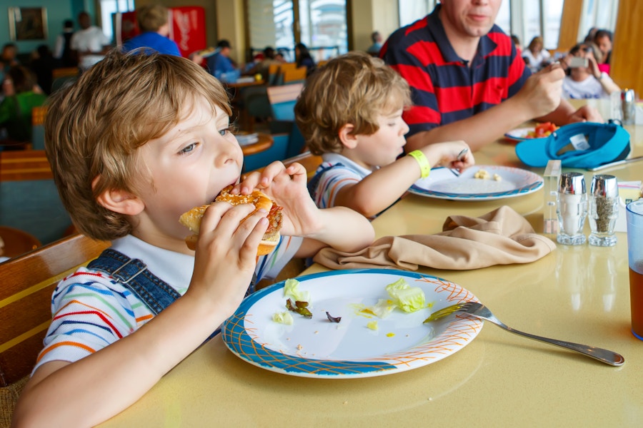 Two preschool boys eating kids hamburgers and salads at a restaurant with their father