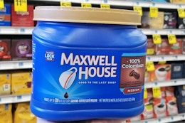 person holding a canister of Maxwell House ground coffee