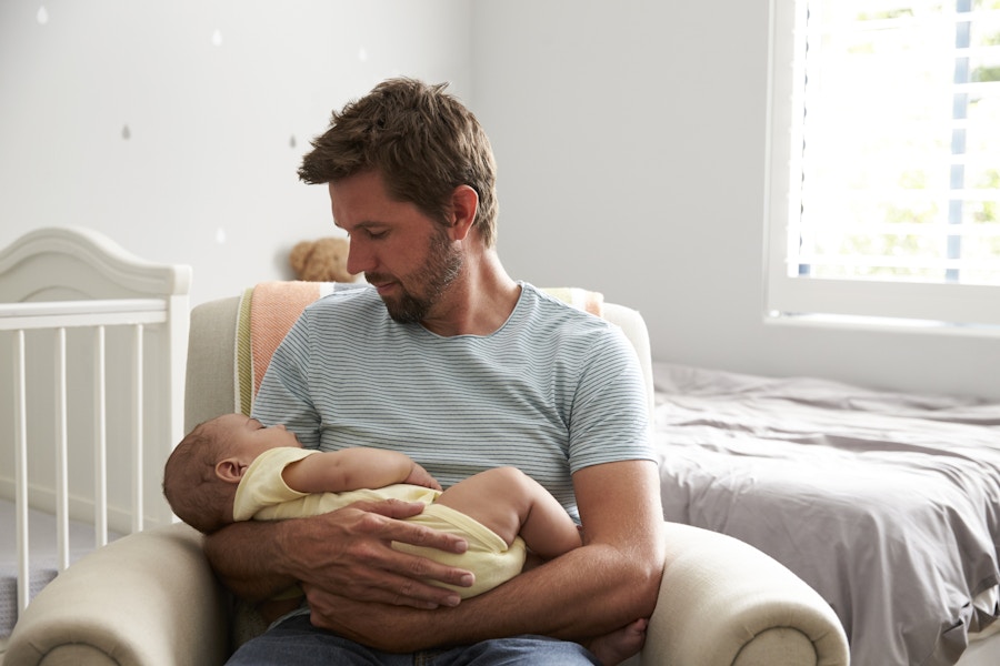 A parent sitting in a nursery holding a baby