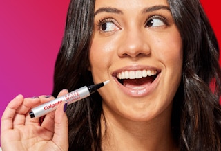 a woman holding a teeth whitening pen near her teeth