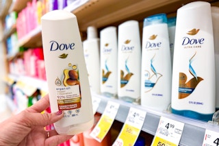 hand holding a bottle of Dove shampoo in front of a shelf with sale tags