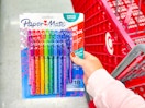 hand holding an 18-pack of paper mate pens in front of a target cart