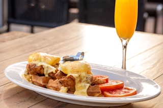 Chicken and Waffles breakfast next to a drink glass at The Cheesecake Factory.